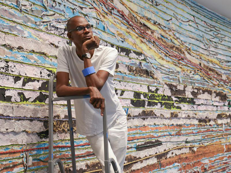 
			
				
				“My practice is décollage and collage at the same time. Décollage: I take it away; collage: I immediately add it right back. It’s almost like arhythm. I’m a builder and a demolisher. I put up so I can tear down…In archaeological terms, I excavate and I build at the same time.” Bradford discusses his inspiration and process in a <a href="https://art21.org/read/mark-bradford-politics-process-and-postmodernism/"
				target="_blank">2011 interview with Art21.
				<a href="https://www.latimes.com/entertainment/arts/miranda/la-et-cam-mark-bradford-hauser-wirth-20180219-htmlstory.html"
				target="_blank">LA Times spoke with Bradford in 2018 about his prolific career, the influence of comic books, and art in the era of Trump.
				Bradford talks with Thelma Golden about his relationship with the medium of painting and experiences of being “othered” in a 2015 <a href="https://youtu.be/5NO7T6Zpj9I"
				target="_blank">video interview in conjunction with his <a href="https://www.hauserwirth.com/hauser-wirth-exhibitions/5494-mark-bradford-be-strong-boquan"
				target="_blank">first show at Hauser & Wirth Gallery, New York. Bradford credits his approach to an early desire to escape labels of artistic identity and a search “for peace, and quiet…a place where I could figure all this out. And for me it was abstraction. Abstraction gave me the freedom to play… I want a space where I can play and be vulnerable and not know. In the shadows….body is removed and stays in the shadows, what you see are the details and the things I’m working out.”
			
	