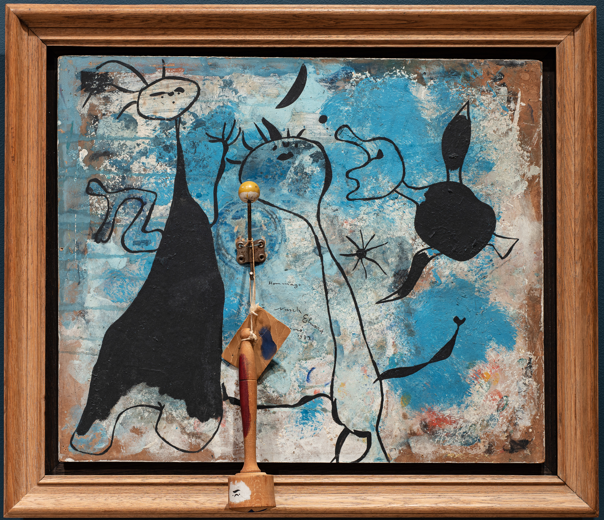 Joan Miró’s playful yet meticulous compositions evolved from a tension between his poetic impulses and his sensitivity toward the ruthless realities of war-torn Europe. Though he found affinity with Surrealism’s devotion to the subconscious, and is considered a critical member of the broader avant garde inter-war movement, Miró resisted labels throughout his experimental, multi-media career. Typical for the Catalan artist, the initial impression of abstraction in Hommage à Nusch Eluard quickly fades to reveal fanciful human and natural forms.The two figures on the left are poet Paul Éluard, one of the founders of Surrealism, and his wife, Nush Éluard. Nusch was also an artist, and frequently modeled for her husband’s friends. The backdrop of celestial symbols and the avian creature flying beside the couple are recurring motifs in Miró’s oeuvre. Many artists associated with Surrealism embraced birds as symbolic transitory beings with the ability to move between the earthly and heavenly realms, the real and the fantastic. The intriguing addition of a grafted metal coat hook with wooden knob and mallet exemplifies Miró’s delight in working beyond the expected norms of artistic medium. Download this study guide.
