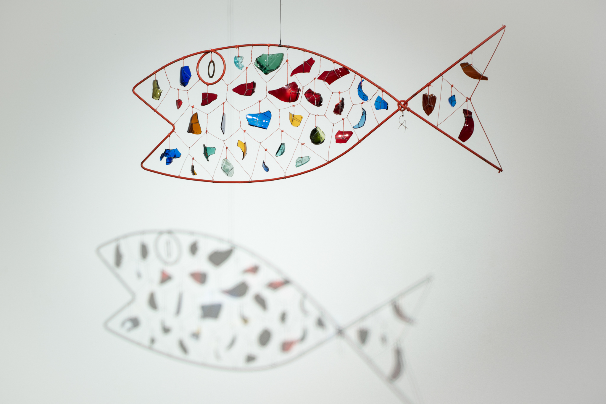 
		Alexander Calder was born into a family of artists – his mother was a painter and his father and grandfather were sculptors – but initially resisted a career in the arts. Instead he pursued a degree in mechanical engineering. After enrolling at the Art Students League in New York in 1923, this background provided the foundations for the signature mobiles that would become the core of his prolific oeuvre. These delicately balanced constructions are hinged together with metal wire and weighted by biomorphic shapes that appear to move on their own, swayed by the slightest breath of air. In each sculpture, the poetic possibilities of motion are an essential element. Fish recalls a subject explored in some of the Calder’s earliest mobiles and is one of just twelve mature sculptures with this formal composition. Encased by a metal frame and held taught by wire and string, the suspended pieces of colored glass become glittering scales that cast ever-changing compositions of shadows as ambient air currents animate the mobile in unexpected ways. <a href="images/JSMA Research Guide-Alexander Calder.pdf"
				target="_blank">Download this study guide.
	